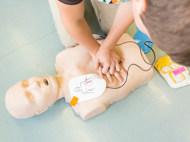 CPR training being performed on manikin with AED pads